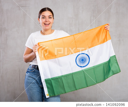Joyful smiling young woman waving flag of India against gray wall background Joyful smiling young woman waving flag of India against gray wall background 141092096