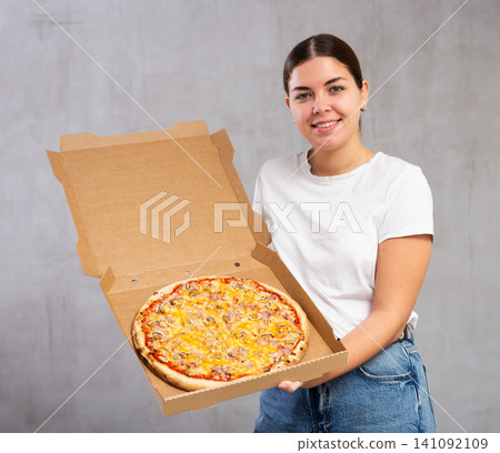 Photo of pizza held by smiling young woman against gray background Photo of pizza held by smiling young woman against gray background 141092109