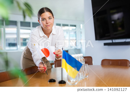 Young lady sets miniatures flags of Ukraine and Japan for international negotiations Young lady sets miniatures flags of Ukraine and Japan for international negotiations 141092127