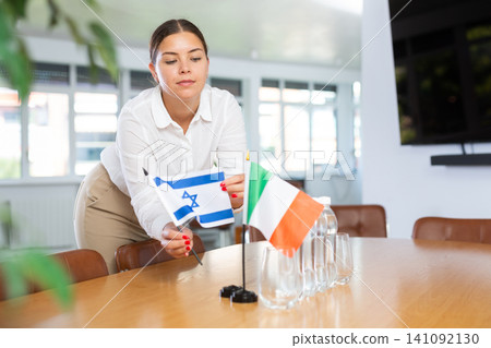 Young woman puts flags of Israel and Italy on table in office Young woman puts flags of Israel and Italy on table in office 141092130