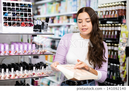 Female customer chooses face powder in cosmetic store Female customer chooses face powder in cosmetic store 141092140