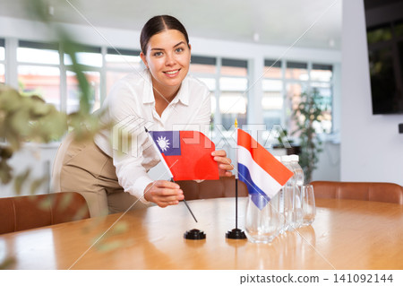 Young lady sets miniatures flags of Netherlands and Taiwan for international negotiations Young lady sets miniatures flags of Netherlands and Taiwan for international negotiations 141092144