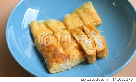 roll omelette stuffed with chesse and rice on blue plate, delicious food in the morning roll omelette stuffed with chesse and rice on blue plate, delicious food in the morning 141092170