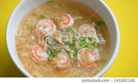 rice soup with shrimp in white bowl on yellow background rice soup with shrimp in white bowl on yellow background 141092180