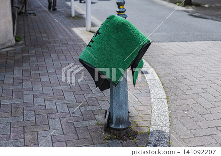 Green store mats drying on poles on the sidewalk Green store mats drying on poles on the sidewalk 141092207