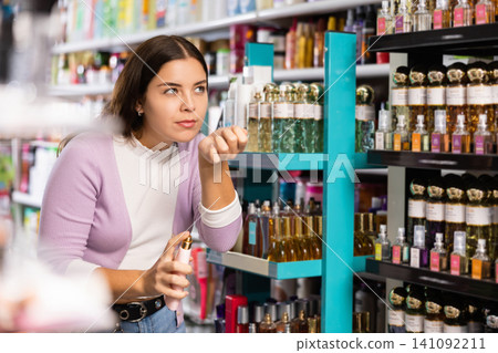 Stylish woman smelling perfume tester, choosing perfume in cosmetic shop 141092211