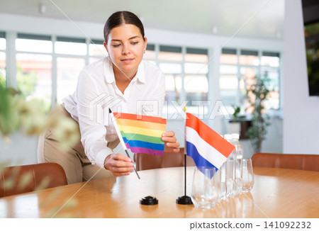 Young lady sets miniatures flags of Netherlands and LGBT for international negotiations 141092232
