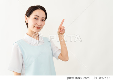 A woman wearing a light blue apron; a caregiver image. A woman wearing a light blue apron; a caregiver image. 141092348