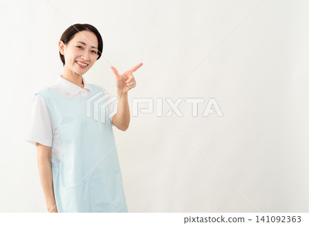 A woman wearing a light blue apron; a caregiver image. A woman wearing a light blue apron; a caregiver image. 141092363