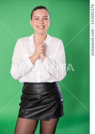 Portrait of happy girl in a white blouse and black skirt on green background 141092378