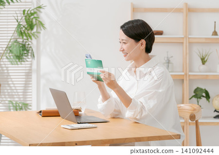 A woman looking at a passbook and smiling A woman looking at a passbook and smiling 141092444
