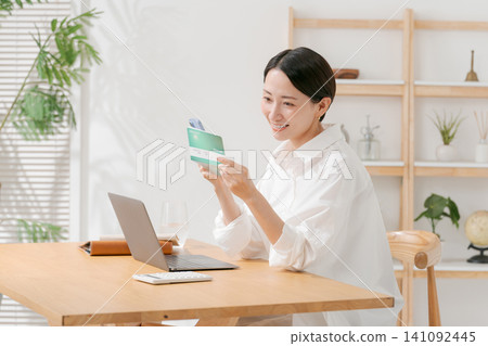 A woman looking at a passbook and smiling A woman looking at a passbook and smiling 141092445