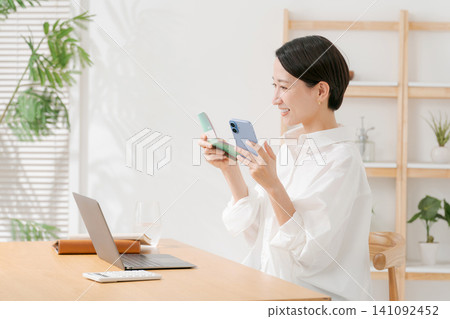 A woman looking at a passbook and smiling A woman looking at a passbook and smiling 141092452