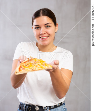Pleased young woman holding piece of pizza Pleased young woman holding piece of pizza 141092640