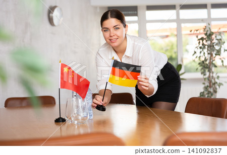 Young female attendant putting up flags for international negotiations between china and germany Young female attendant putting up flags for international negotiations between china and germany 141092837