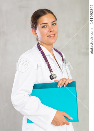 Happy female doctor standing with file in hands Happy female doctor standing with file in hands 141092843
