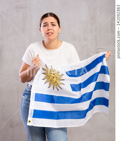 Sad girl with flag of Uruguay in her hands Sad girl with flag of Uruguay in her hands 141092863