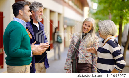 Four smiling seniors enjoying outdoor conversation and friendship Four smiling seniors enjoying outdoor conversation and friendship 141092957