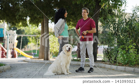 Couple interacting with golden retriever in a park Couple interacting with golden retriever in a park 141093021
