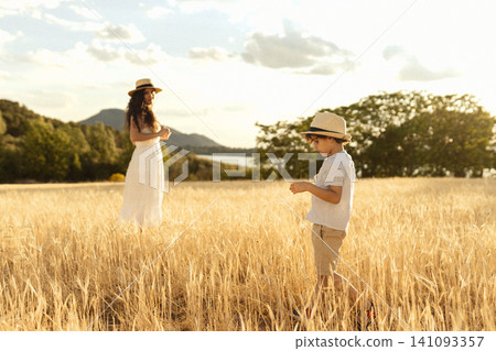 Mother and child walking in golden wheat field Mother and child walking in golden wheat field 141093357