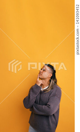 Latino man thinking with hand on chin looking up 141093452