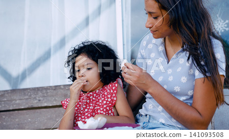 Latino mother and child eating snack outdoors 141093508