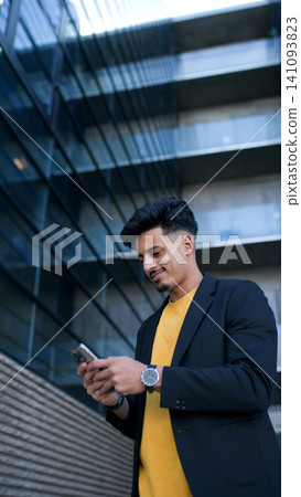 Moroccan businessman smiling and checking smartphone in city 141093823