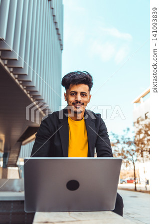 Moroccan man working on laptop outdoors smiling Moroccan man working on laptop outdoors smiling 141093839