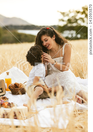 Mother and son enjoying picnic in golden wheat field Mother and son enjoying picnic in golden wheat field 141093870