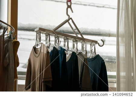 A scene by the window on a snowy day, where laundry is being dried indoors using a connected hanger. A scene by the window on a snowy day, where laundry is being dried indoors using a connected hanger. 141094652