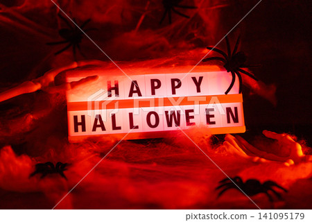 Atmospheric Halloween concept designed for seasonal greetings announcements or promotional messages combining illuminated typography HAPPY HALLOWEEN with classic spooky decorations to symbolize myster Atmospheric Halloween concept designed for seasonal greetings announcements or promotional messages combining illuminated typography HAPPY HALLOWEEN with classic spooky decorations to symbolize myster 141095179