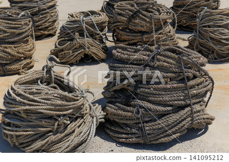 Fishing ropes bundled together in a circle and placed in the fishing port. Fishing ropes bundled together in a circle and placed in the fishing port. 141095212