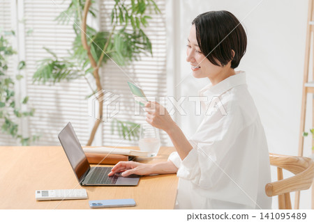 A woman looking at a passbook and smiling A woman looking at a passbook and smiling 141095489