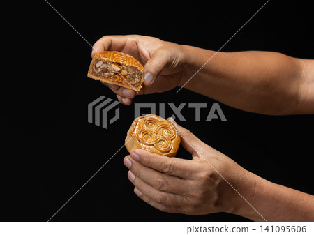 Hand Holding Traditional Mooncakes for Mid-Autumn Festival Celebration on dark Background. Hand Holding Traditional Mooncakes for Mid-Autumn Festival Celebration on dark Background. 141095606