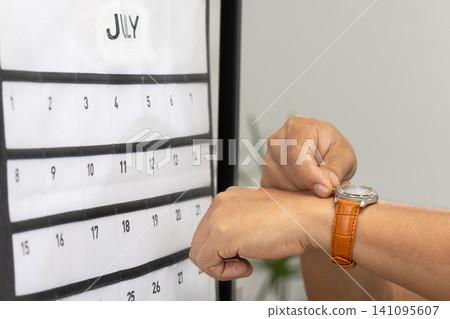Senior Asian man with dementia struggles to set the time and day on his watch. Senior Asian man with dementia struggles to set the time and day on his watch. 141095607