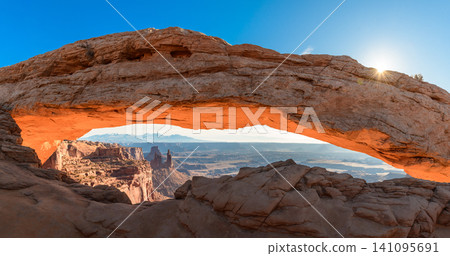 Breathtaking sunrise illuminates Mesa Arch in Utah USA, casting warm glow across majestic desert landscape. iconic rock formation evokes sense of wonder and peaceful beauty Breathtaking sunrise illuminates Mesa Arch in Utah USA, casting warm glow across majestic desert landscape. iconic rock formation evokes sense of wonder and peaceful beauty 141095691