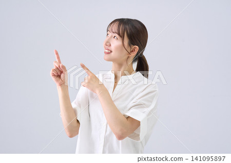 Japanese woman pointing with both hands Japanese woman pointing with both hands 141095897