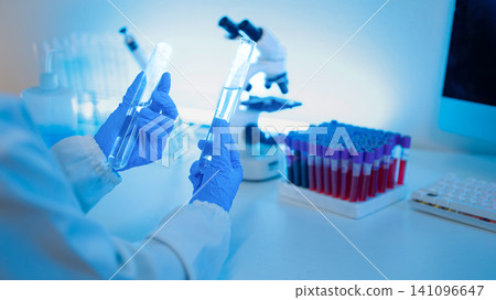 Laboratory Scientist Holding Test Tubes with Microscope and Blood Sample Rack in Medical Research Lab Laboratory Scientist Holding Test Tubes with Microscope and Blood Sample Rack in Medical Research Lab 141096647