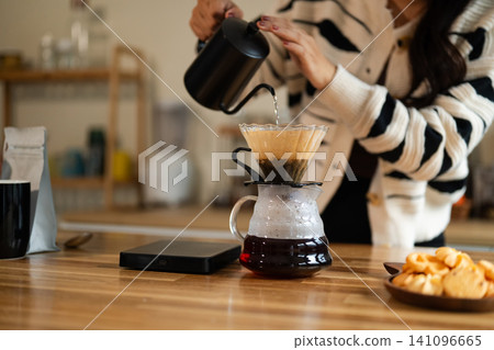 Woman Brewing Pour Over Coffee at Home Kitchen Counter with Gooseneck Kettle and Glass Carafe Woman Brewing Pour Over Coffee at Home Kitchen Counter with Gooseneck Kettle and Glass Carafe 141096665