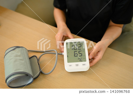 Person Checking Digital Blood Pressure Monitor with Systolic Diastolic and Pulse Readings on Wooden Table Person Checking Digital Blood Pressure Monitor with Systolic Diastolic and Pulse Readings on Wooden Table 141096768