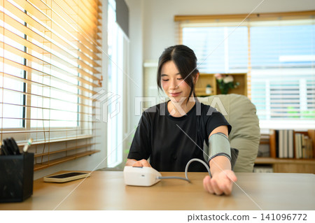 Young Asian Woman Measuring Blood Pressure at Home with Digital Sphygmomanometer 141096772