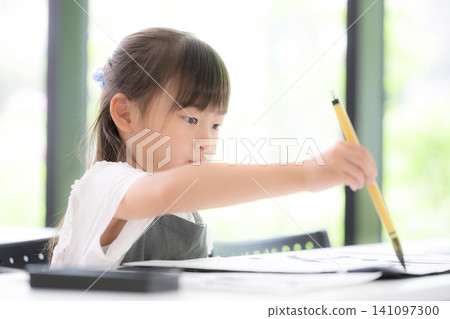 一位小學生正在專心練習書法,用毛筆書寫文字。學習書法的日本兒童表情嚴肅認真。 一位小學生正在專心練習書法,用毛筆書寫文字。學習書法的日本兒童表情嚴肅認真。 141097300