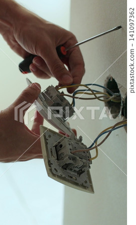 Vertical video Professional electrician working on a home electrical system. Close up man installing a wall socket at new apartment or house. Vertical video Professional electrician working on a home electrical system. Close up man installing a wall socket at new apartment or house. 141097362