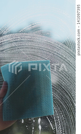Vertical video Woman in rubber gloves sprays window cleaner from a spray bottle onto the windows glass. Housewife hands in rubber gloves cleaning windows close up. Cleaning glass window with a cloth Vertical video Woman in rubber gloves sprays window cleaner from a spray bottle onto the windows glass. Housewife hands in rubber gloves cleaning windows close up. Cleaning glass window with a cloth 141097395