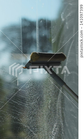 Vertical video Woman hands wipes with a scraper dirty window close up. Washes a window, glass with a brush. Concentration of cleanliness, cleaning companies. Vertical video Woman hands wipes with a scraper dirty window close up. Washes a window, glass with a brush. Concentration of cleanliness, cleaning companies. 141097399