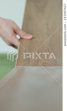 Vertical video Worker, lays laminate on a green backing. Technology and process. Repair of the floor of the house. Vertical video Worker, lays laminate on a green backing. Technology and process. Repair of the floor of the house. 141097427