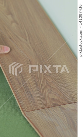 Vertical video Close-up of a man in an apartment laying laminate on the floor. Floor in a Home. Closeup on male hands. Vertical video Close-up of a man in an apartment laying laminate on the floor. Floor in a Home. Closeup on male hands. 141097436