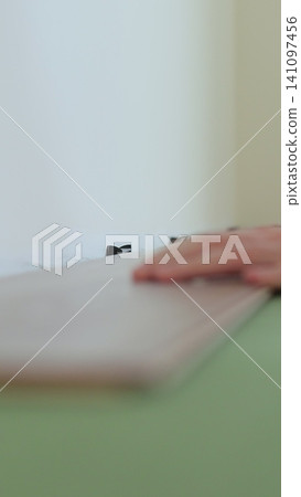 Vertical video Man lays laminate flooring on the floor in a room. Repair of the floor of the house. Vertical video Man lays laminate flooring on the floor in a room. Repair of the floor of the house. 141097456