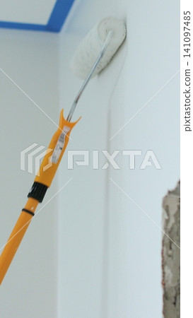 Vertical video Man painting wall in white color with roller. Builder, tools, apartment renovation. Vertical video Man painting wall in white color with roller. Builder, tools, apartment renovation. 141097485