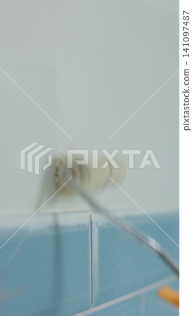 Vertical video Man worker using roller to paint the walls in the house in white color. Room renovations at house. Vertical video Man worker using roller to paint the walls in the house in white color. Room renovations at house. 141097487